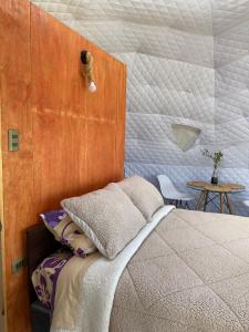 a bedroom with a bed and a wooden wall at Milenaria Glamping in Panguipulli