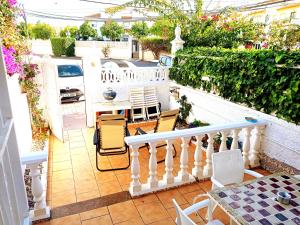 uma varanda com um corrimão branco, uma mesa e cadeiras em Maravilloso Bungalow em Gran Alacant