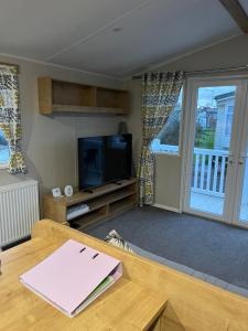 a living room with a table and a tv at Lorraine's Caravan Holiday in Morecambe