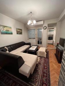 a living room with a black leather couch and a table at Two luxury bedroom apartment D&V in Berovo