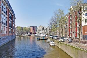 アムステルダムにあるCity-centre, Canal-house, luxurious , stylish bedroom, ensuite bathroom, own entranceの車を横に止めた川