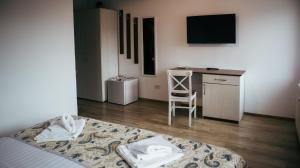 a bedroom with a bed and a desk with a chair at AristoCat Hotels Rasnov in Râşnov