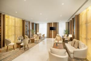 una hall con sedie e tavoli bianchi e una televisione di فندق جايدن-Jayden Hotel a Medina