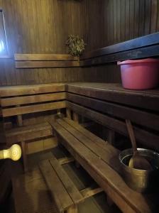 un banco de madera en una sauna con un cubo en Mežvītoli, en Mercendarbe