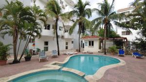 una piscina frente a un hotel con palmeras en Residence Caribe, en Guayacanes