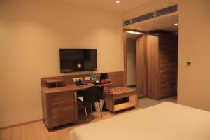 a hotel room with a desk with a television on the wall at Hotel Krystal in Sāngli