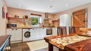 a kitchen with a table and a washer and dryer at Mwsogl - Luxurious Family Fishing Lodge Near Aberaeron With Private Fishing in Cross Inn