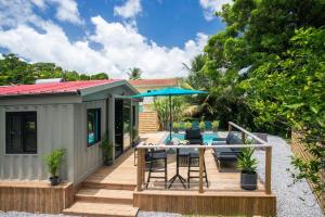 een tiny house met een terras met een tafel en stoelen bij Éco-Chic Bungalow by Bungazur in Saint-Joseph