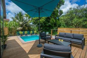 a patio with a couch and an umbrella and a pool at Éco-Chic Bungalow by Bungazur in Saint-Joseph