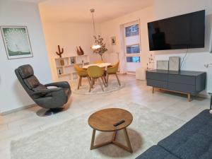 a living room with a tv and a table and chairs at Cozy Apartment: Design Superior Suite Zentral - Küche - Balkon in Cloppenburg