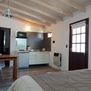 a room with a kitchen with a bed and a table at Cabañas Paso de Viento in El Chalten