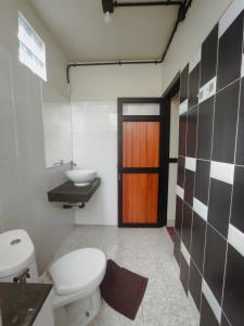 La salle de bains est pourvue de toilettes, d'un lavabo et d'une porte. dans l'établissement Villa Rumah Hijau Syariah, à Cihanjuang 1