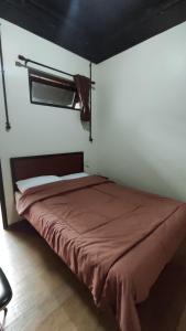 Schlafzimmer mit einem Bett mit einer roten Tagesdecke in der Unterkunft Villa Rumah Hijau Syariah in Cihanjuang 1