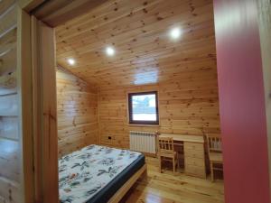 1 dormitorio en una cabaña de madera con cama y escritorio en Chata pod lasem, en Zatory