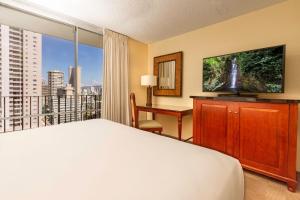 um quarto com uma cama, uma secretária e uma televisão em Beautiful Suites at Ohia Waikiki Honolulu em Honolulu