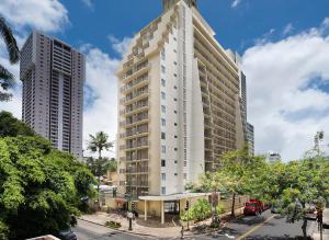 a tall white building on a street with two tall buildings at Beautiful Suites at Ohia Waikiki Honolulu in Honolulu