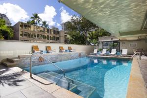 a swimming pool with lounge chairs and a building at Beautiful Suites at Ohia Waikiki Honolulu in Honolulu