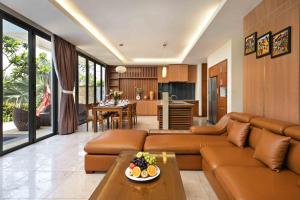 a living room with a brown couch and a kitchen at Blue Ocean Villas Danang in Da Nang