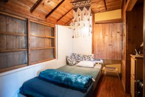 1 dormitorio con 1 cama en una habitación con paredes de madera en 【Camp House by port Side】 貸切1組の古民家/離島、美ら海への拠点, en Motobu