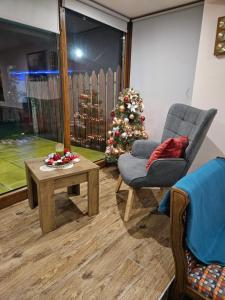 a living room with a christmas tree and a chair and a table at Юндовата къща in Beli Iskar