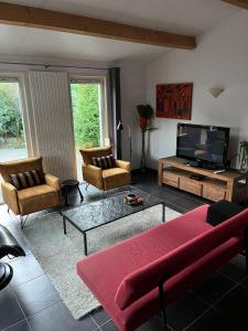 - un salon avec un canapé et une télévision dans l'établissement Ruime en comfortabele bungalow aan bosrand, à Lage Mierde
