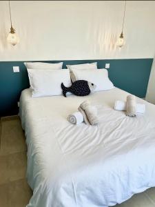 a large white bed with a stuffed animal on it at Villa Bréhat vue mer et jacuzzi in Tréveneuc