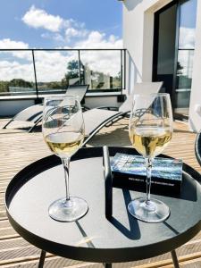 two glasses of white wine on a table on a balcony at Villa Bréhat vue mer et jacuzzi in Tréveneuc
