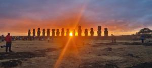 a group of people standing around a group of statues at sunset at Hostal Henua Roa 2 in Hanga Roa
