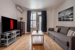 a living room with a couch and a tv at 5-STAR Prime Location - Bright Condo in Montreal