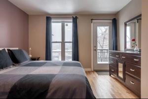 a bedroom with a bed and a dresser and windows at 5-STAR Prime Location - Bright Condo in Montréal