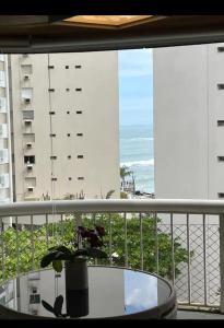 a balcony with a table and a view of the ocean at Flat botique Guarujá in Guarujá