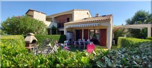 a house with a table and chairs in the yard at Hameau du Rivage 224 - Rez de jardin climatisé - 3 étoiles - 6 Pers - Jardin - Piscine - Vélos prêtés - Parking - 400m de la plage de La Lagune - WIFI in Saint-Cyprien