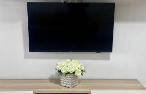 a vase of flowers sitting on a table under a tv at Lake House - Bucuresti in Bucharest