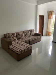una sala de estar con un sofá marrón en una habitación en Apartment near Colombo Airport en Katunayaka
