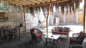 eine Terrasse mit Stühlen, Tischen und einer Hängematte in der Unterkunft La Casa de Joan in Máncora