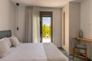 a bedroom with a bed and a desk and a window at Marble Luxury Suites in Karteros