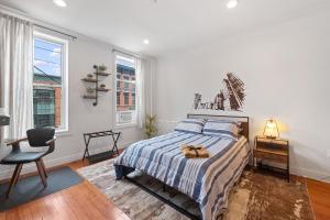 een slaapkamer met een bed, een stoel en ramen bij Large Home Near NYC In Hoboken Sleeps 6 in Hoboken