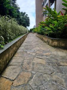 un chemin en pierre dans un jardin avec des plantes dans l'établissement APT. ESPETACULAR NO PORTO REAL RESORT - BELA VISTA 3 SUÍTES, à Mangaratiba