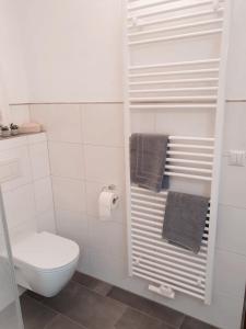 a white bathroom with a toilet and towels at Fewo Rosalie in Norddeich