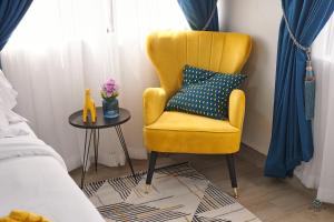 a yellow chair and a table in a bedroom at Charming Rooftop Apartments with Great view & Free Strong Wi-Fi - 40percent Long-stay Disc- Red Lotus Oasis in Accra