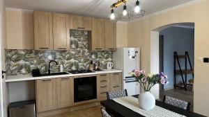 a kitchen with wooden cabinets and a table with a vase of flowers at Sasanka LZ in Lądek-Zdrój