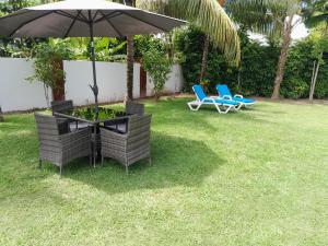 a table and chairs under an umbrella in a yard at Island Charm of Praslin in Victoria