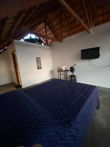 um quarto com uma cama azul e uma televisão em Chalé Vista Encanto dos Montes em Monte das Gameleiras
