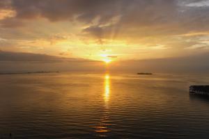 um pôr do sol sobre a água com o pôr do sol em BestView Maisons Private Beach Suites Port Dickson em Porto Dickson