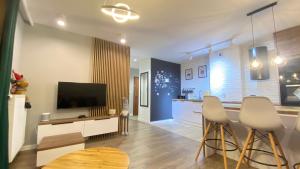 a living room with a television and two bar stools at Apartament Złocień in Krakow