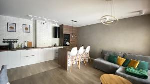 a kitchen and living room with a couch and chairs at Apartament Złocień in Krakow +6 photos