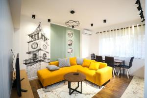 a living room with a yellow couch and a clock tower at Tirana Center Apartment - Your Cosy Corner in Tirana