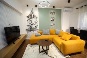 sala de estar con sofá amarillo y TV en Tirana Center Apartment - Your Cosy Corner, en Tirana
