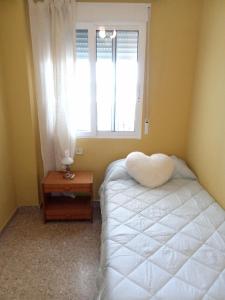 um quarto com uma cama branca e uma janela em Apartamento tradicional em Canet d'En Berenguer