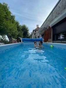 two children playing in a blue swimming pool at Ancien domaine de Chartreux avec jacuzzi in Tullins